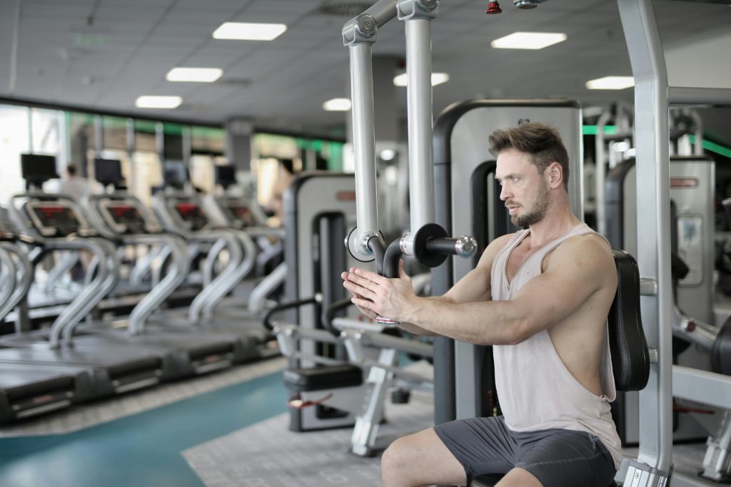 A muscular man working out on gym equipment, showcasing strength and determination indoors.